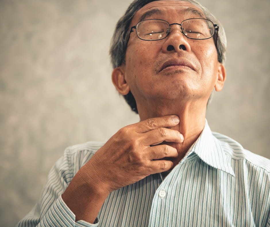 Man in discomfort while touching his throat.